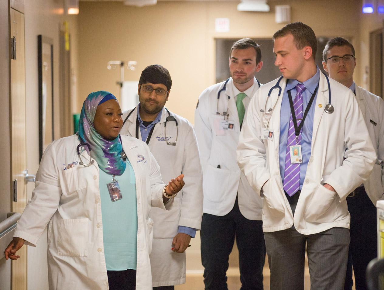 A group of medical students walking and talking with their supervising doctor