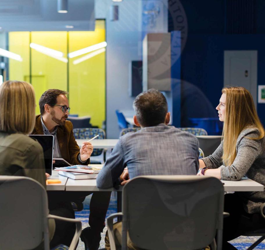 Students and faculty in meeting room around table